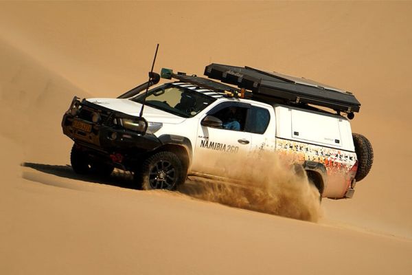 4x4 auto op gravelweg in het uitgestrekte landschap van Namibië