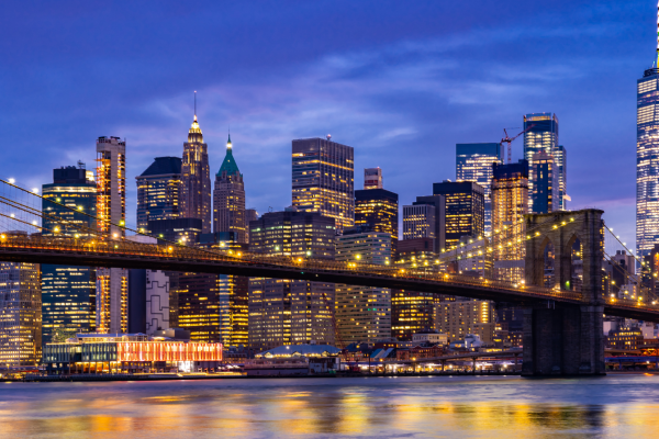 New York skyline bij avond gezien vanaf een brug met sfeervolle stadsverlichting.