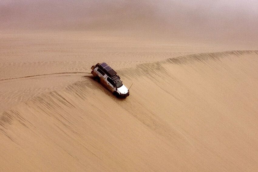 “Off-road Toyota Hilux Expedition Xtra Cab met verhoogde bodemvrijheid op zandpad in Namibië.”