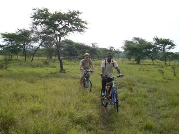 Ranger en reiziger op fietssafari in Lake Mburo National Park tussen zebrapaden en savanne