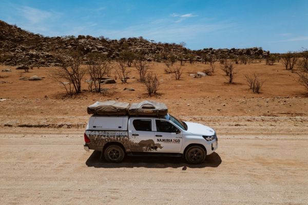 Off-road Toyota Hilux Double Cab Budget 4x4 op zandpad in Namibië.
