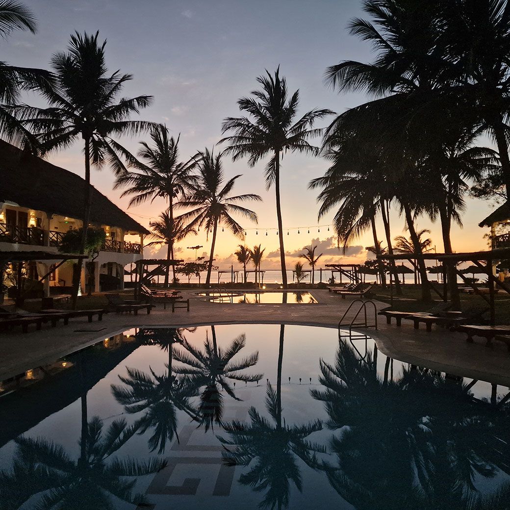 Zwembad van Nest Style Zanzibar bij zonsondergang met warme kleuren boven de oceaan