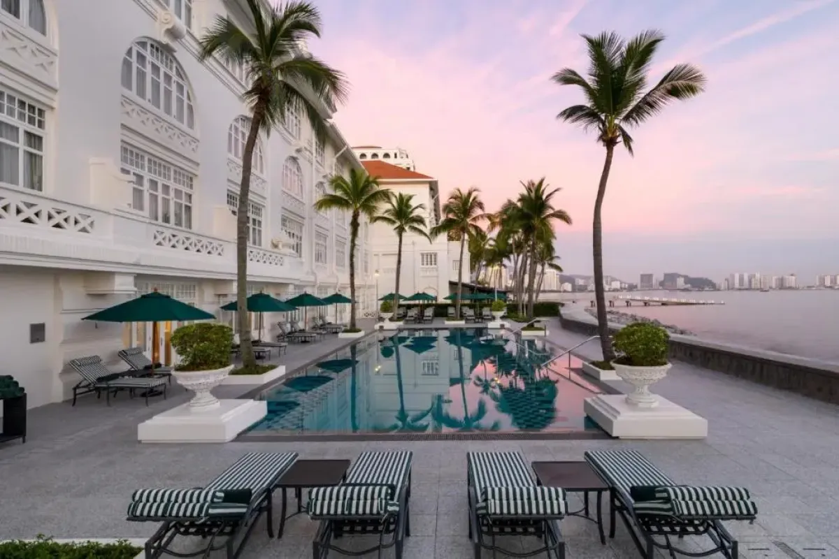 Zwembad met palmbomen aan zee bij Eastern & Oriental Hotel in George Town