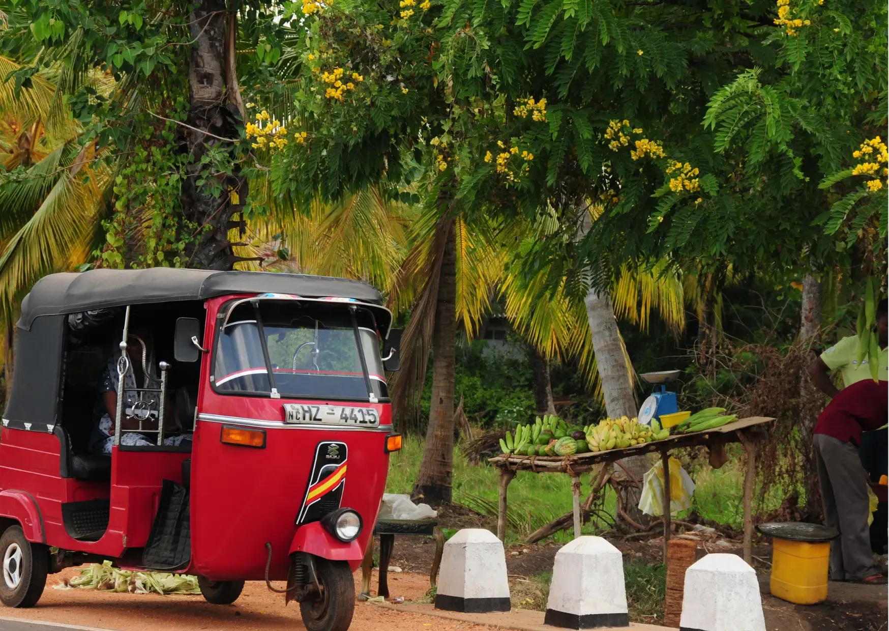 Rode tuk-tuk langs de weg met fruitkraam en palmbomen in Sri Lanka