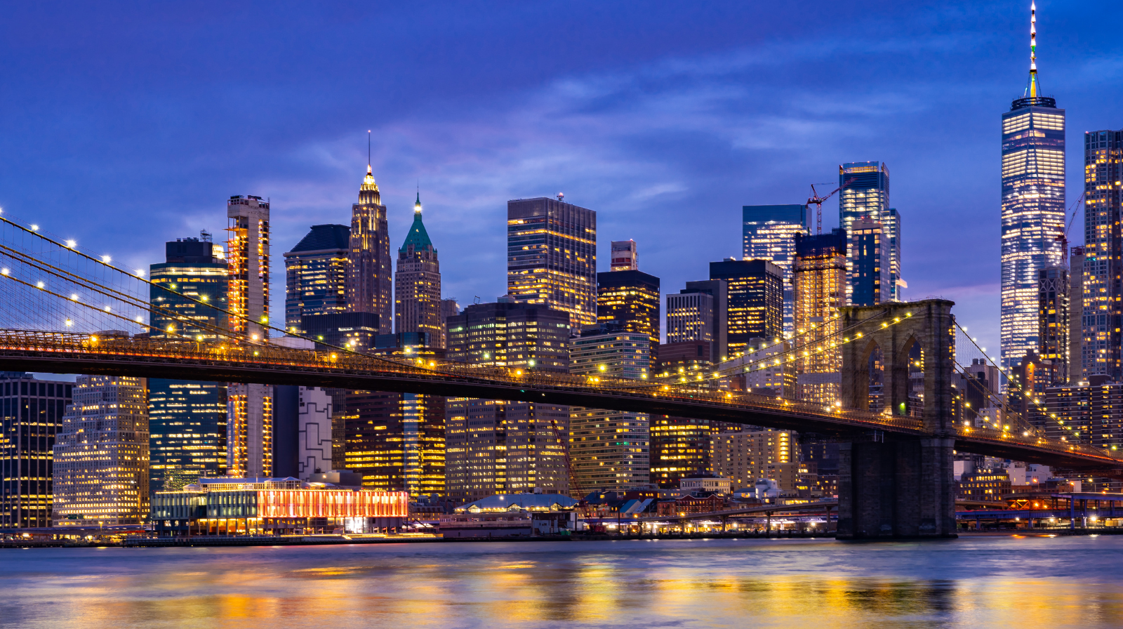 New York skyline bij avond gezien vanaf een brug met sfeervolle stadsverlichting.