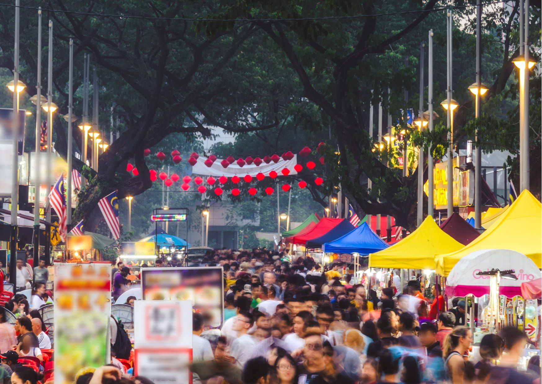 Drukke streetfoodmarkt met kleurrijke kraampjes en bezoekers in Kuala Lumpur