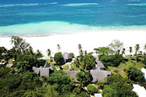 Wit zandstrand bij Eleven Pearl Diani met turquoise zee, rustige sfeer en luxe boutique-ervaring aan de Indische Oceaan.