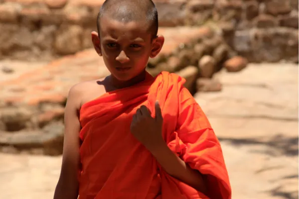 Jonge boeddhistische monnik in oranje gewaad in Sri Lanka