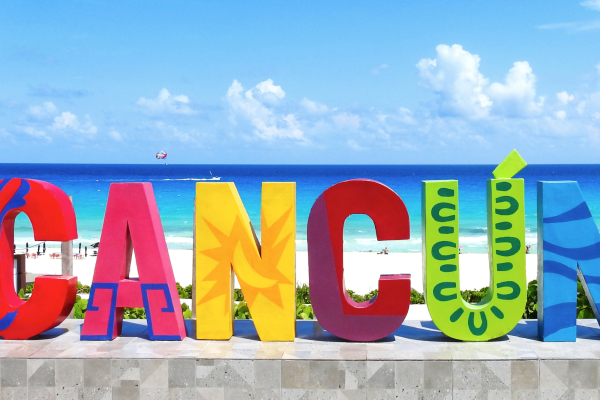 Grote kleurrijke letters Cancún op het strand in Mexico, met wit zand en turquoise Caribische Zee aan de kust van Yucatán.