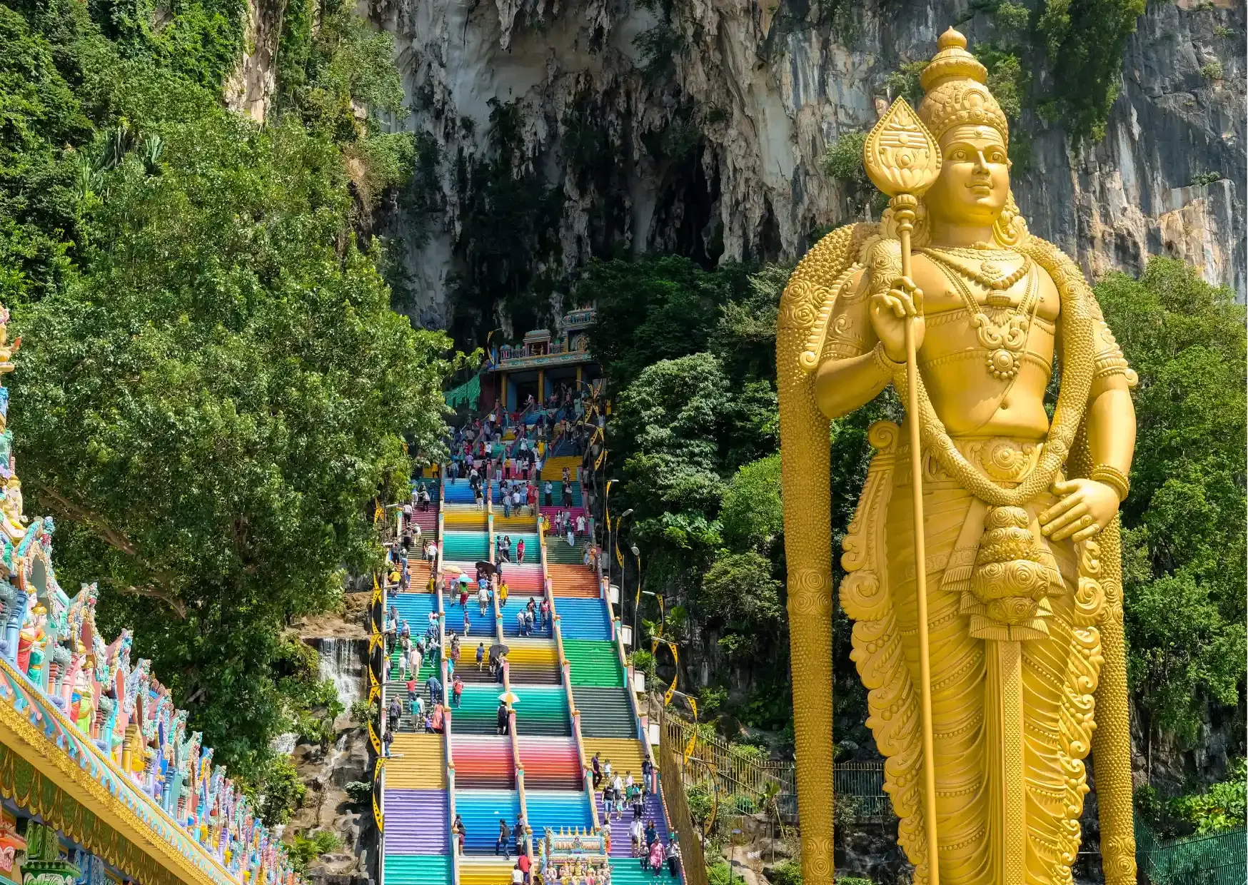 Gouden beeld van Lord Murugan naast de kleurrijke trappen van de Batu Caves