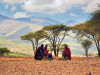 Maasai Mannen zitten bij savanna landschap in Tanzania
