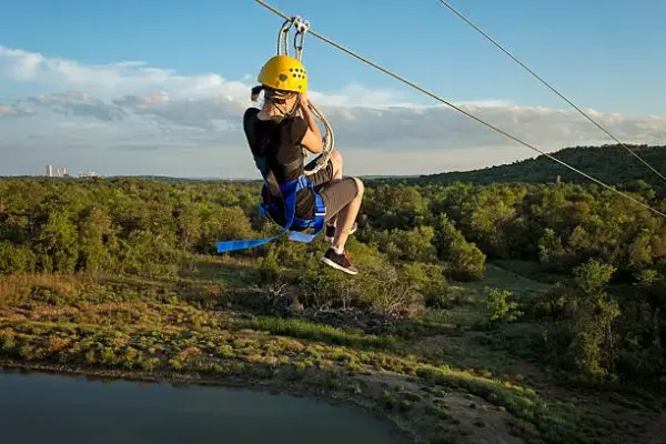 Hazyview_Avontuurlijke reiziger zoeft langs een zipline boven de groene bossen van Hazyview.