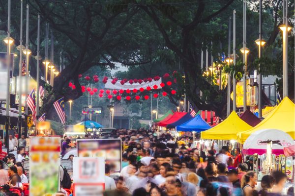 Drukke streetfoodmarkt met kleurrijke kraampjes en bezoekers in Kuala Lumpur