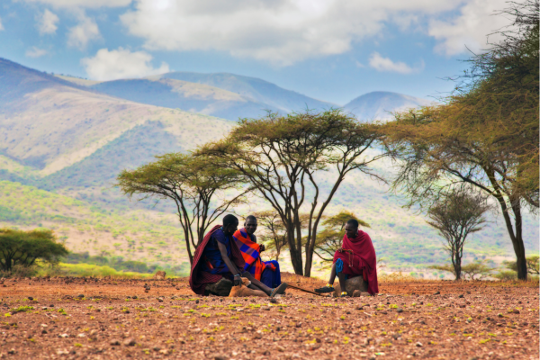 Maasai Mannen zitten bij savanna landschap in Tanzania