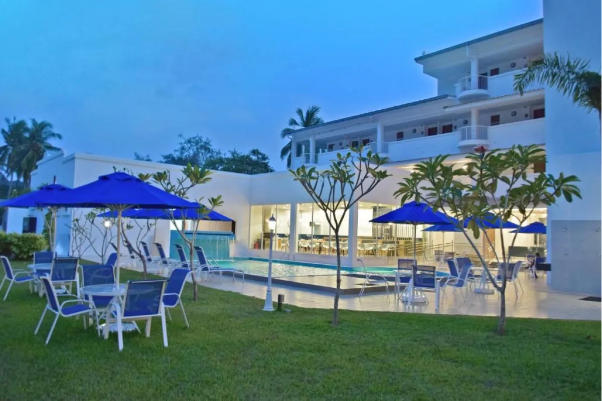 Modern buitenaanzicht van AVI Pangkor Beach Resort met zwembad, terras en blauwe parasols