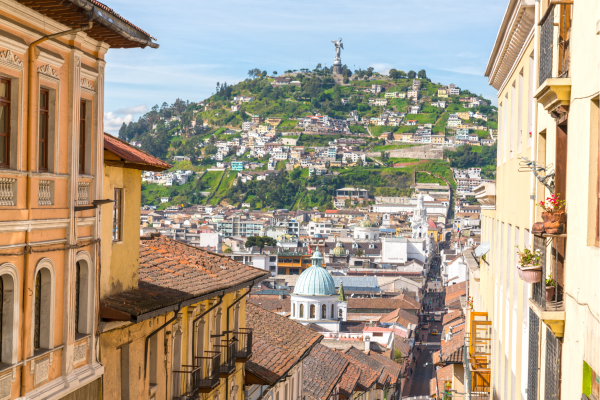 Uitzicht over het historische centrum van Quito met koloniale architectuur, kleurrijke daken en de Andes op de achtergrond.