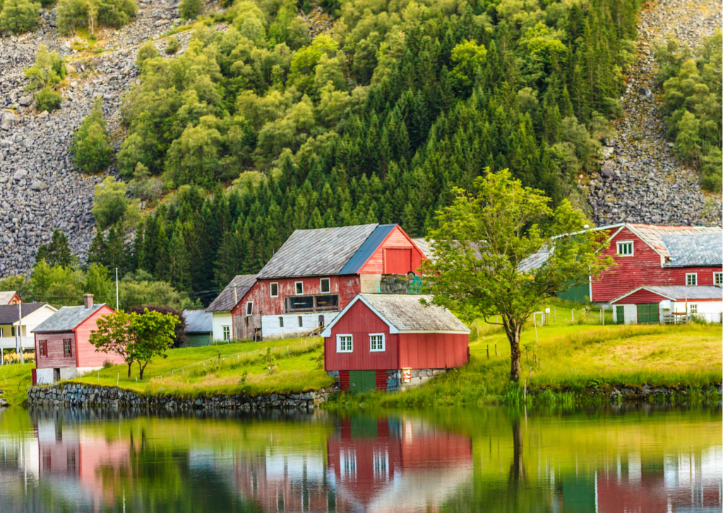 Klein dorp aan een fjord in Noorwegen met kleurrijke huizen, bergen en rustig water.