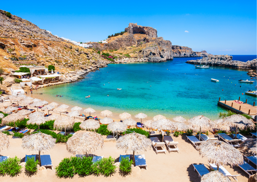 Mediterrane kustlijn in Griekenland met rotsachtige kliffen, blauwe zee en zonovergoten landschap.