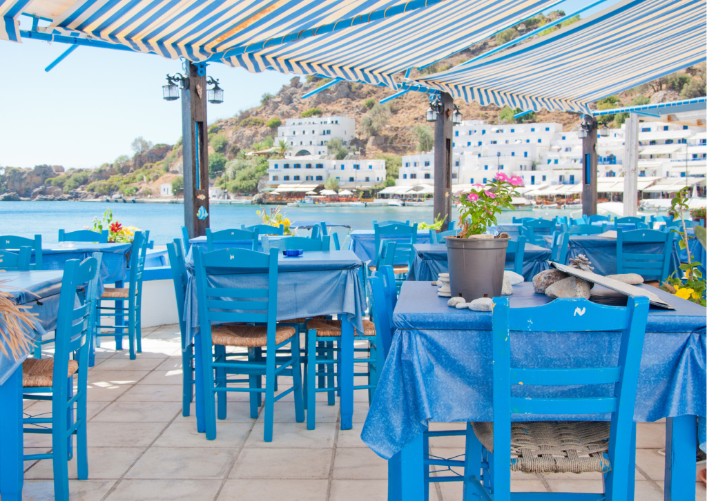 Gezellig Grieks restaurant aan zee met traditionele gerechten, tafels buiten en uitzicht over de Middellandse Zee.