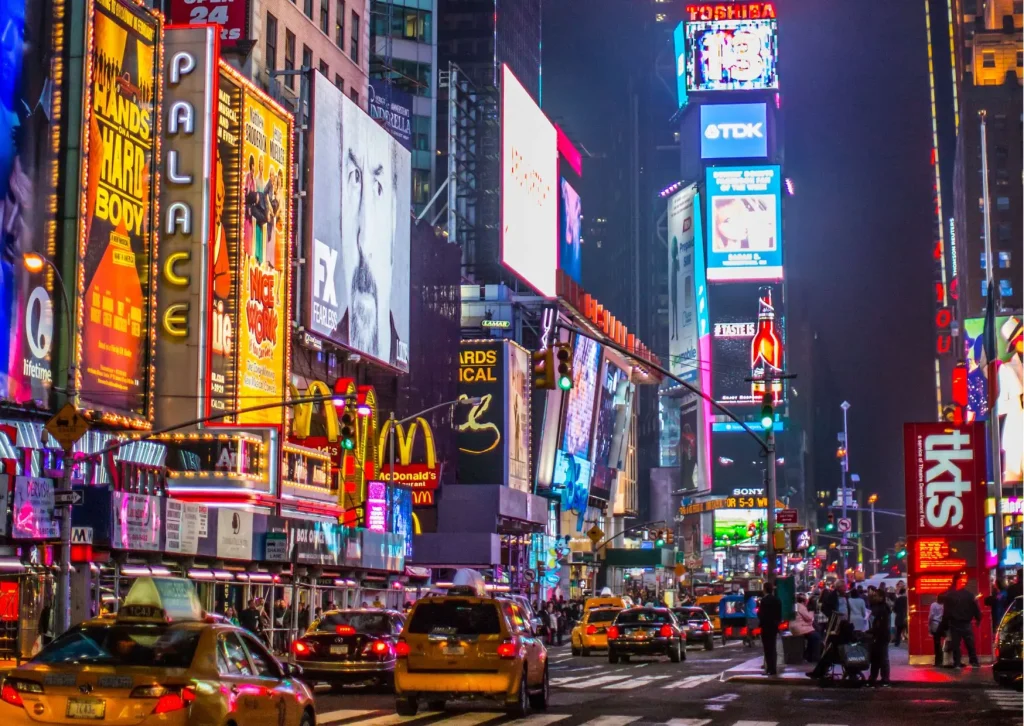 10 redenen waarom New York en een Caribbean cruise de perfecte combinatie zijn. Verlichte reclameborden en drukte op Times Square in New York tijdens de avonduren